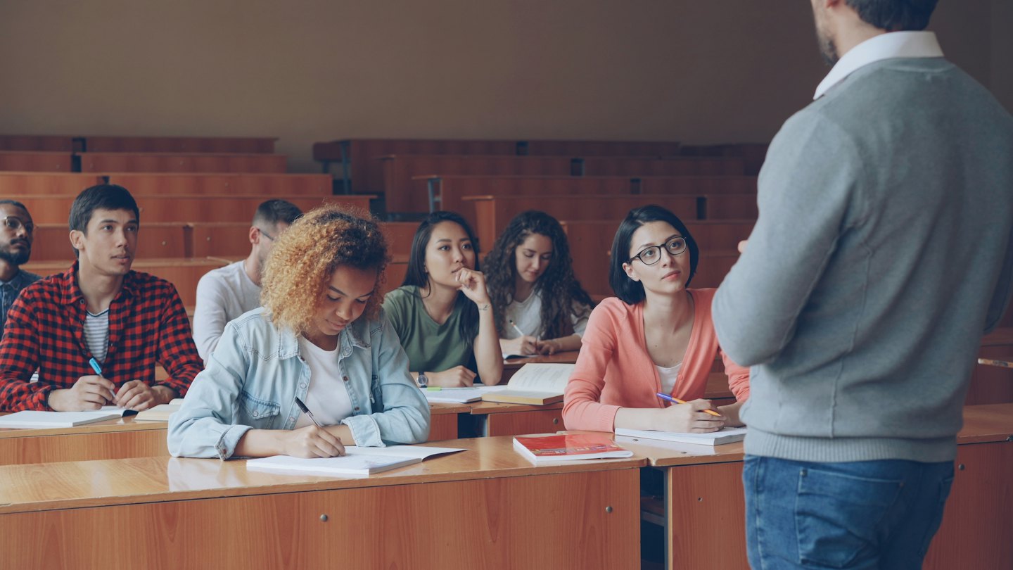 University students paying attention during a lecture in a hall.